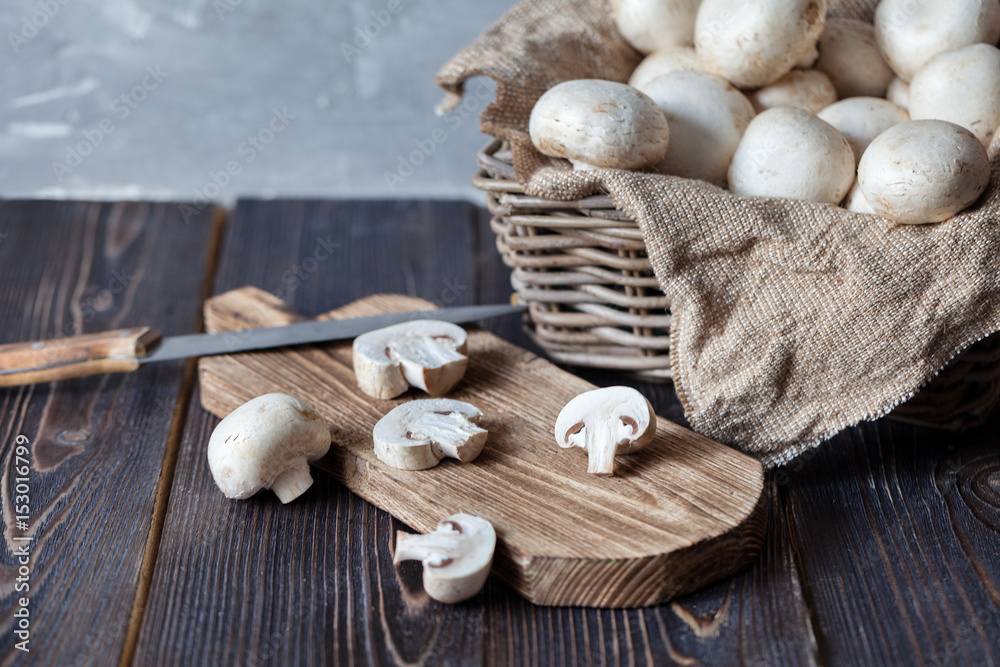 Mushrooms champignons in a basket on a neutral background