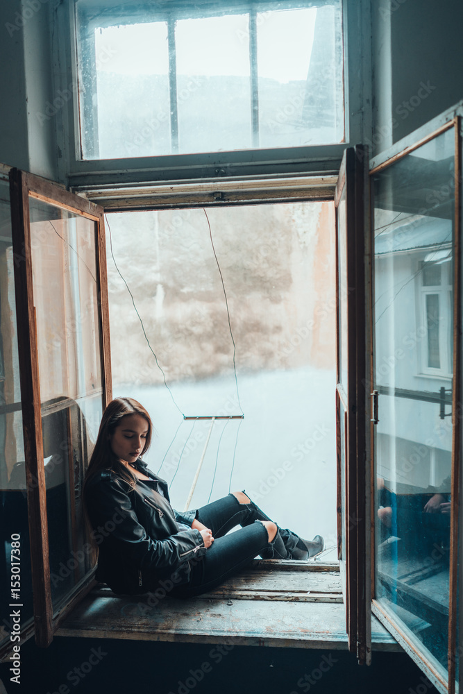beautiful woman poses on a window sill