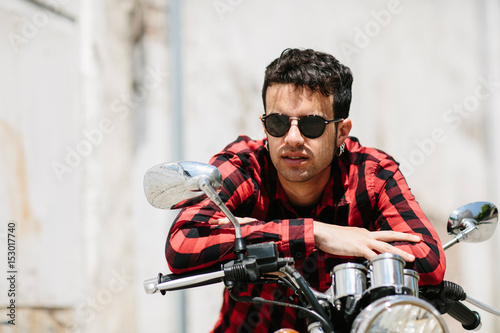 Young man in sunglasses posing on motorcycle photo