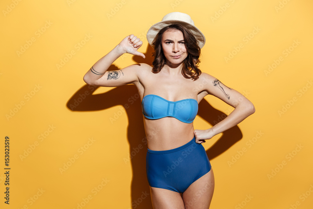 Sad young woman in swimwear showing thumbs down. Sad young woman in swimwear showing thumbs down.
