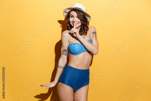 Happy young woman in swimwear showing silence gesture.