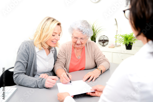 elderly senior woman with daughter signature legacy heritage testament document in a lawyer notary office photo
