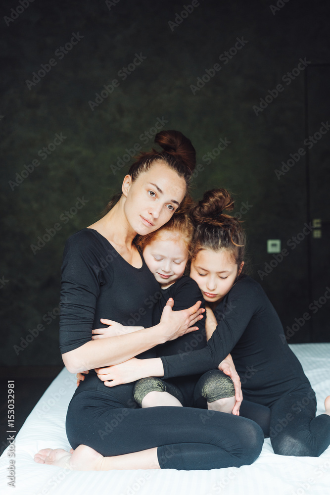 Mom and two daughters have fun on the bed Mom and two daughters have fun on the bed