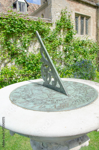 Close up of sundial with old house in background