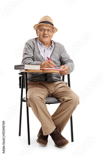 Mature man in a school chair taking notes © Ljupco Smokovski