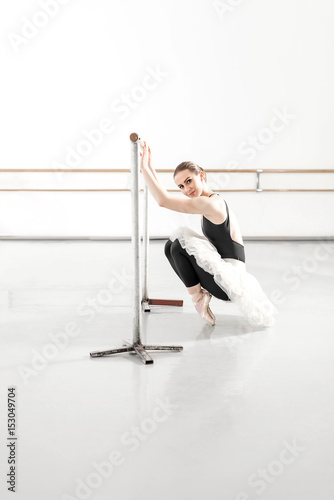 Bellerina stretching in ballet studio with bar