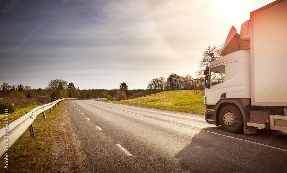 asphalt road on dandelion field with a small truck. lorry moving on sunny evening asphalt road on dandelion field with a small truck. lorry moving on sunny evening
