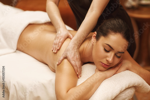 Beautiful woman relaxing receiving body massage at spa center