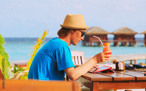 youg man drinking cocktail looking at touch pad on beach resort © nadezhda1906