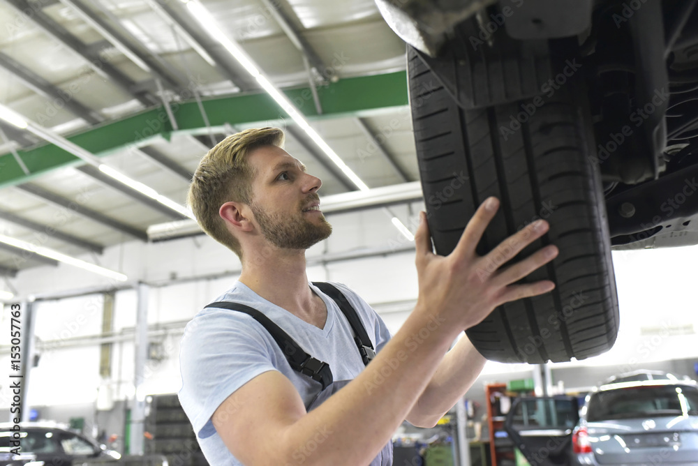 Car mechanic in a workshop changing car tire