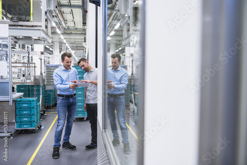 Two men with tablet talking in factory shop floor