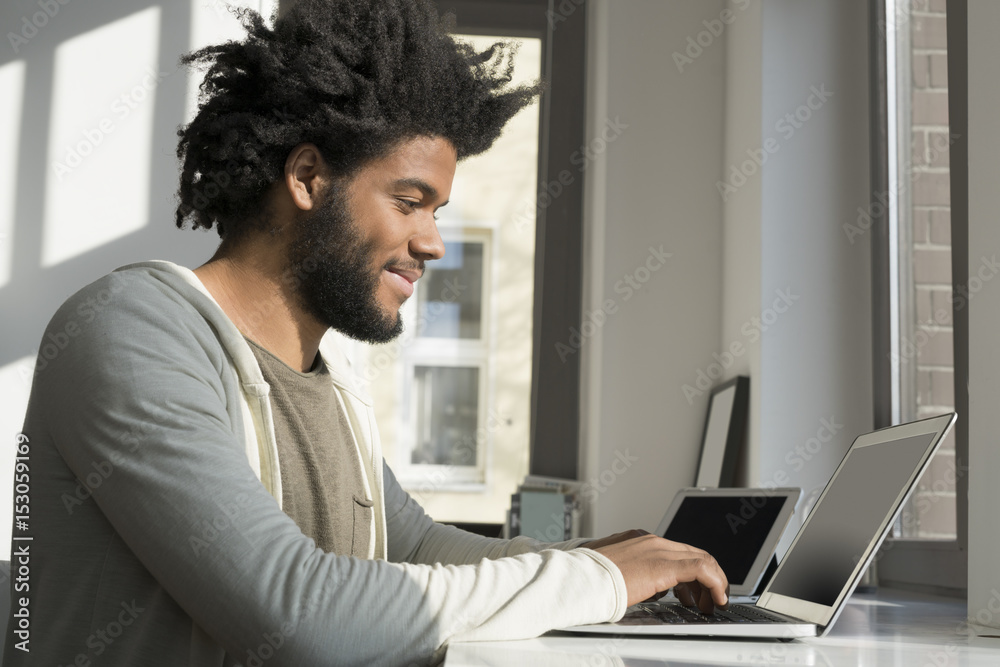 Man working in front of window at home with laptop Man working in front of window at home with laptop
