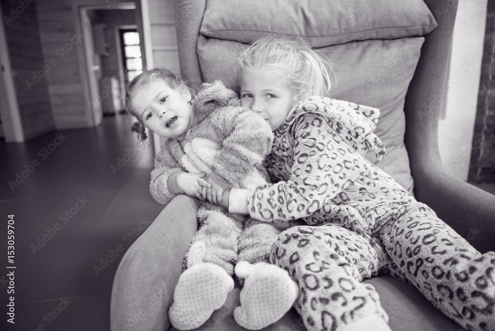 Portrait of a happy little girls sisters. Girls wearing pajamas. Sisters laughing and having fun playing at home. Concept of love and happiness happy family Portrait of a happy little girls sisters. Girls wearing pajamas. Sisters laughing and having fun playing at home. Concept of love and happiness happy family