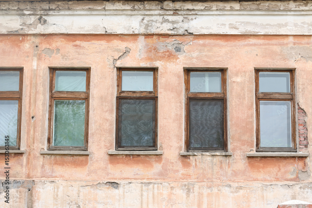 windows on wall of old house with peeling plaster