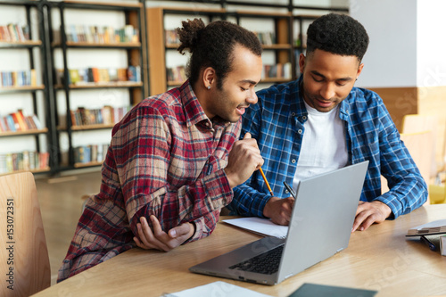 Two multicultural male students studying with laptop