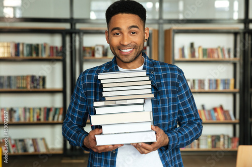Young happy african man student standing in library