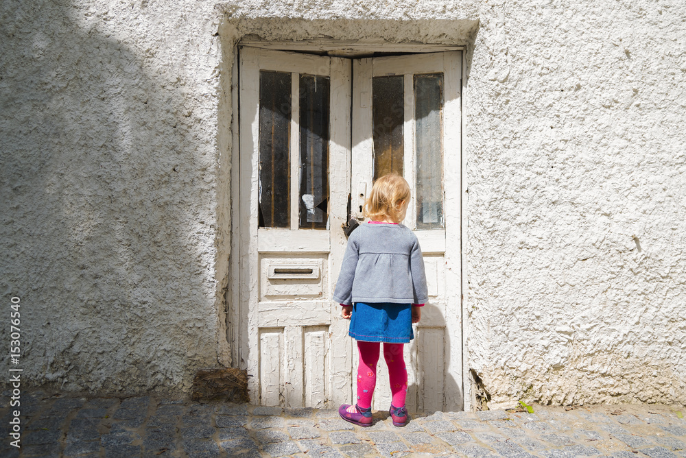 The little girl was staring at the old door in the street