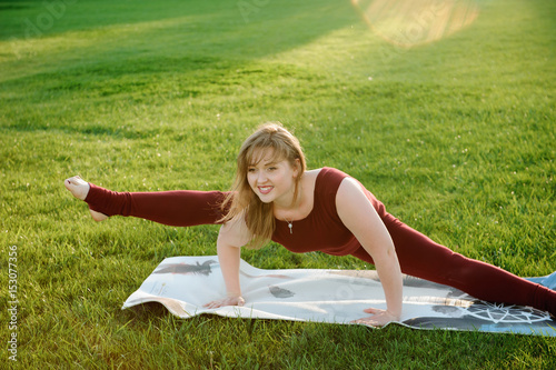 Young beautiful woman doing yoga exercises in park