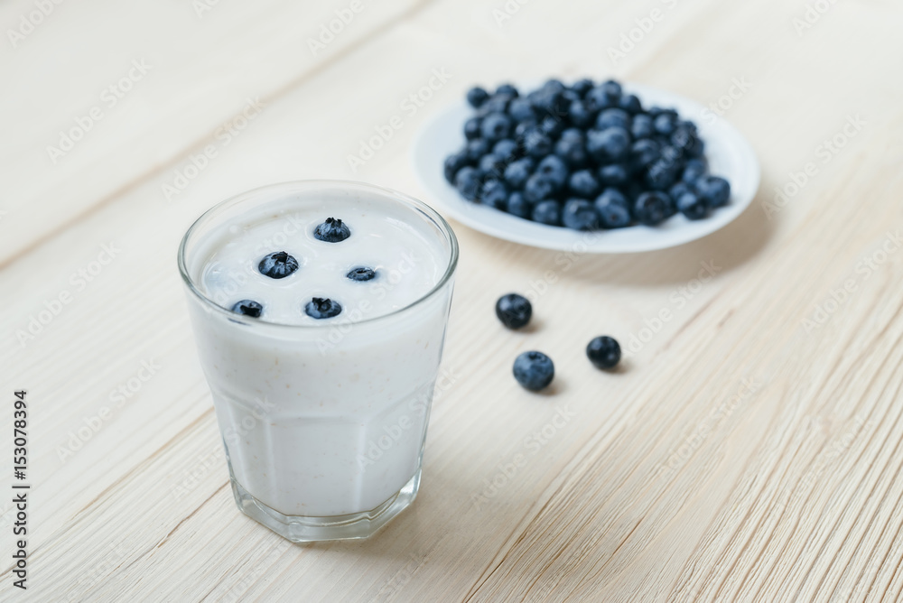 Rustic healthy breakfast with blueberry and yogurt in a glass on a wooden table. Glass of homemade yogurt with ripe berries. Healthy breakfast with vital vitamins. Rustic healthy breakfast with blueberry and yogurt in a glass on a wooden table. Glass of homemade yogurt with ripe berries. Healthy breakfast with vital vitamins.