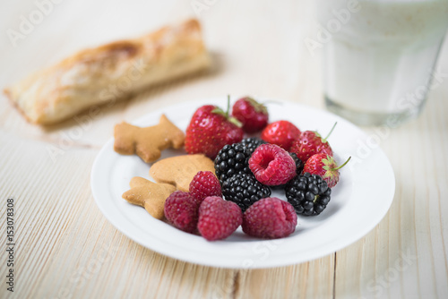 Rustic healthy breakfast with blueberry, raspberry, crackers, small loaf and milk in a glass on a wooden table. Healthy breakfast with vital vitamins.