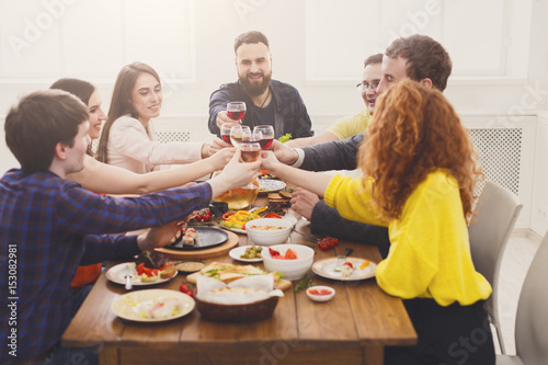 People say cheers clink glasses at festive table dinner party