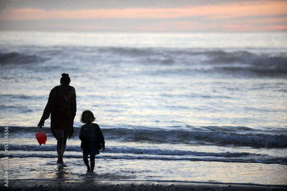 Mutter und kind  spielen in der Abendsonne am Meer 