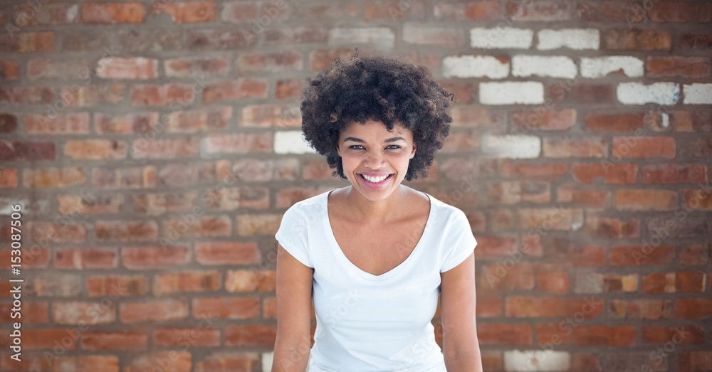 Happy woman with curly hair against brick wall Happy woman with curly hair against brick wall
