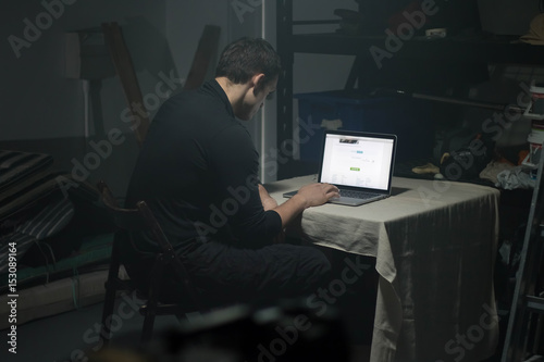 Photography Man using laptop in dark room.
