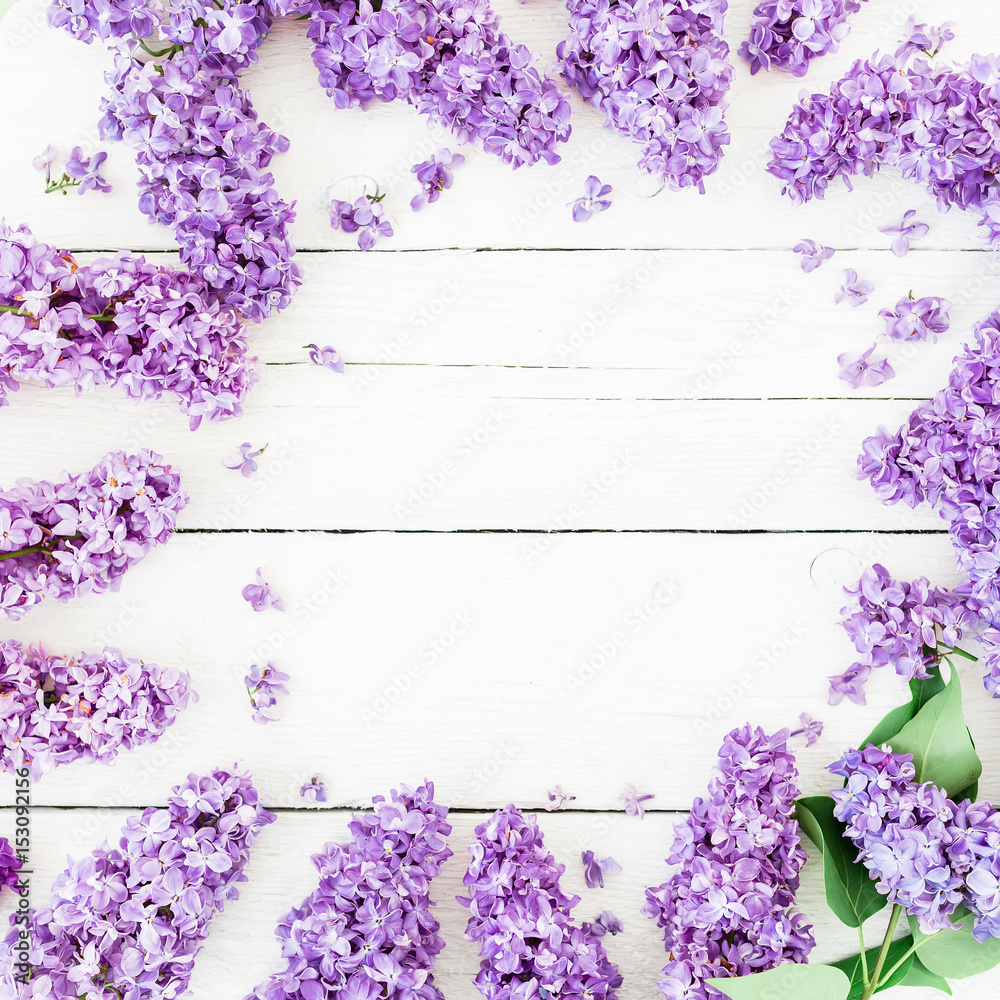 Round frame of lilac branches and leaves on wooden background. Flat lay, top view. Summer pattern