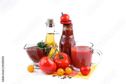Still life of red and yellow tomatoes, bottle of tomato sauce and olive oil on white background.