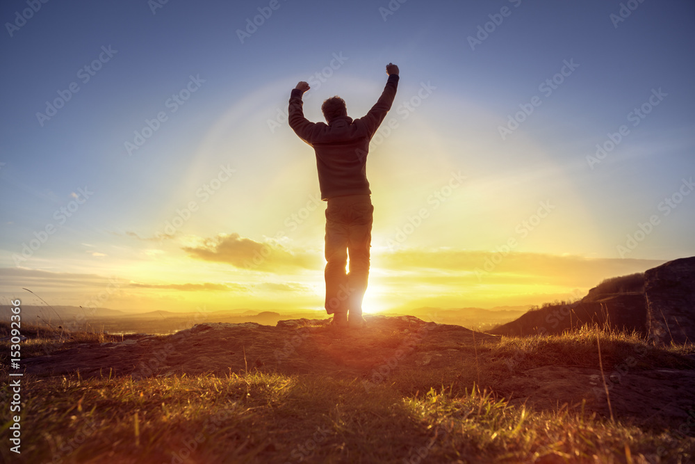 Happy man celebrating winning success against sunset