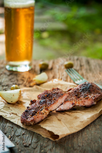 Grilled meat with onion and beer on natural background