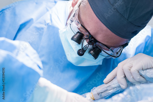 A male dentist in uniform perform dental implantation operation on a patient at dentistry office.