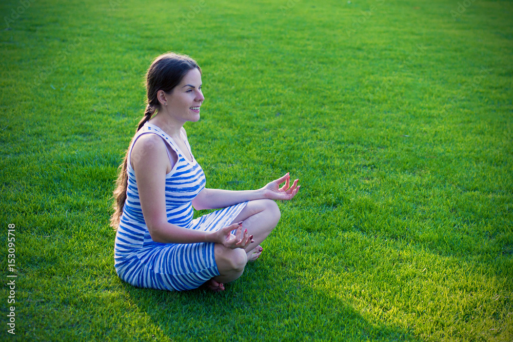 Young woman meditates in yoga asana on green grass Young woman meditates in yoga asana on green grass