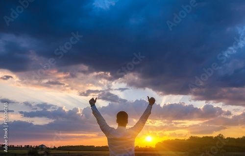 happy businessman, standing in field over wind background with his hands up and thumbs up