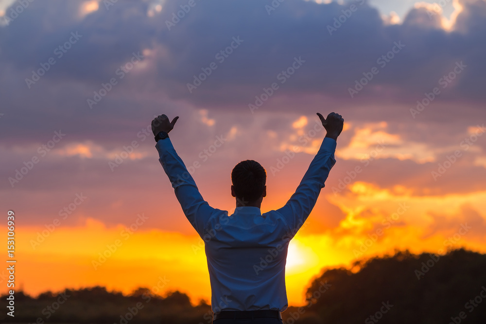 happy businessman, standing in field over wind background with his hands up and thumbs up happy businessman, standing in field over wind background with his hands up and thumbs up