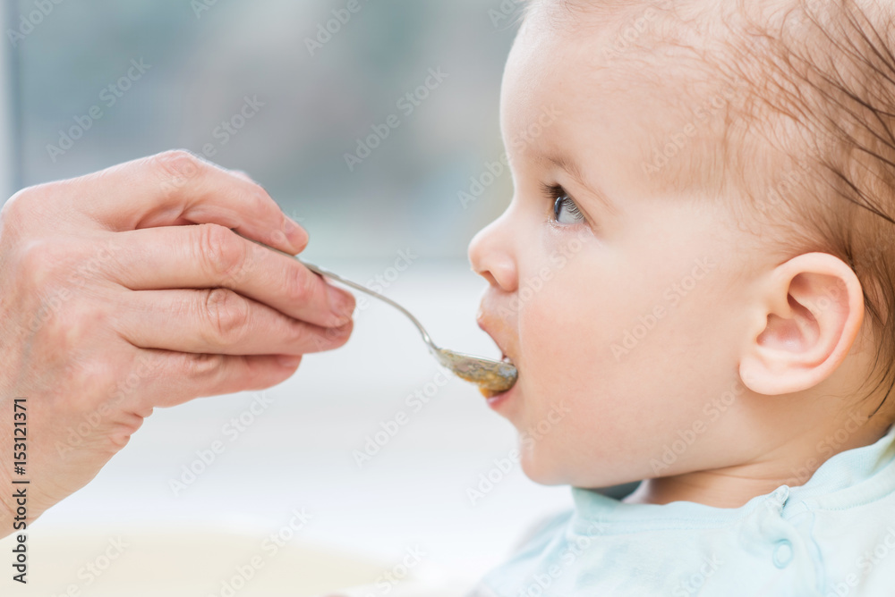 grandmother gives baby food from a spoon grandmother gives baby food from a spoon