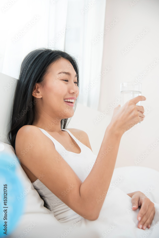 Close up Asian Woman holding glass of water with alarm clock. Close up Asian Woman holding glass of water with alarm clock.