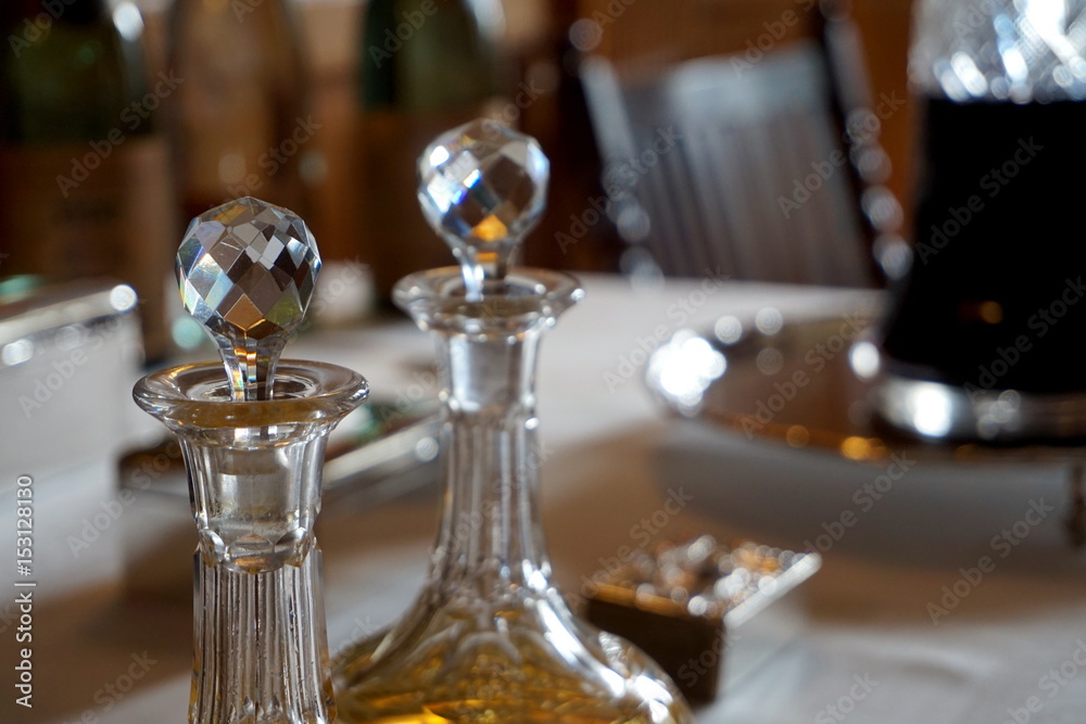 Old glass wine and spirit decanters on an ornate table in natural daylight Old glass wine and spirit decanters on an ornate table in natural daylight