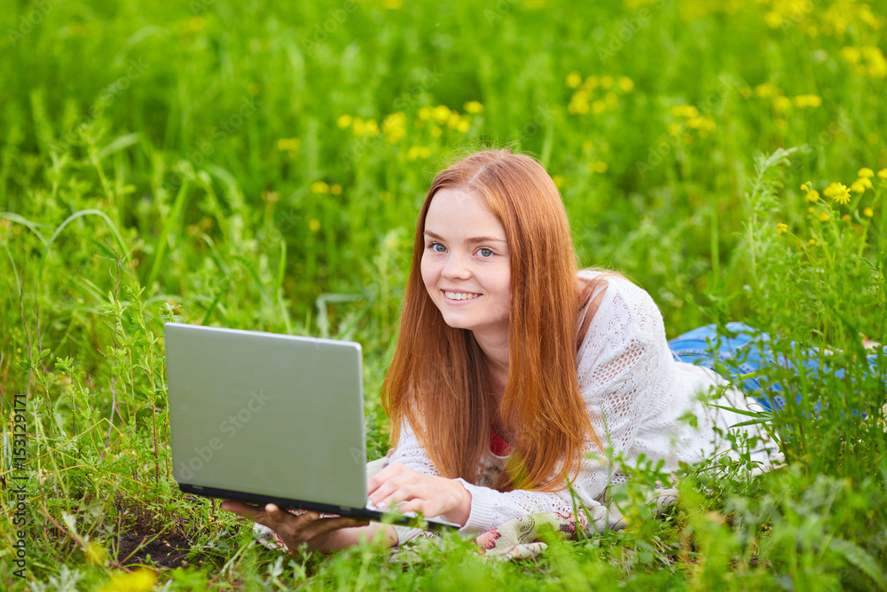 Smiling girl with laptop on grass Smiling girl with laptop on grass