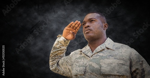 Soldier saluting with black grunge background 