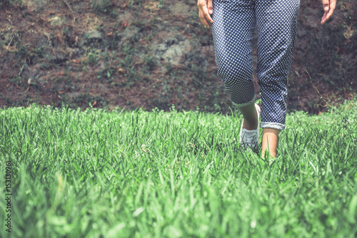 Legs of women walking on a green meadow.