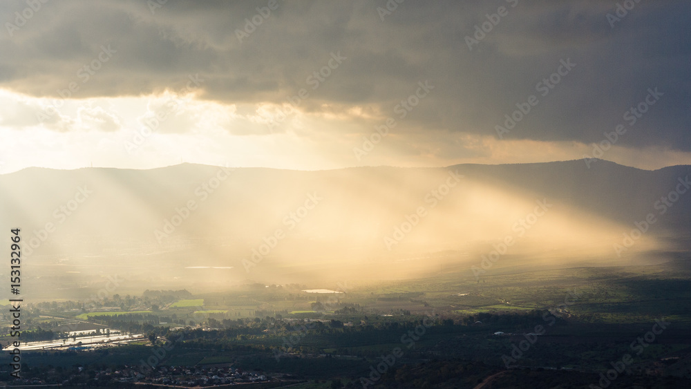 Magnificent landscape of the Golan Heights, the rays of the setting sun make their way through heavy clouds and dispersing the darkness above the valley