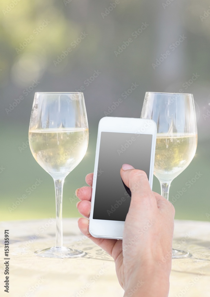 Hand holding phone with two glasses of wine