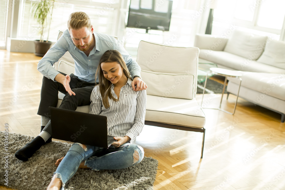 Couple sitting on the floor with laptop in the living room