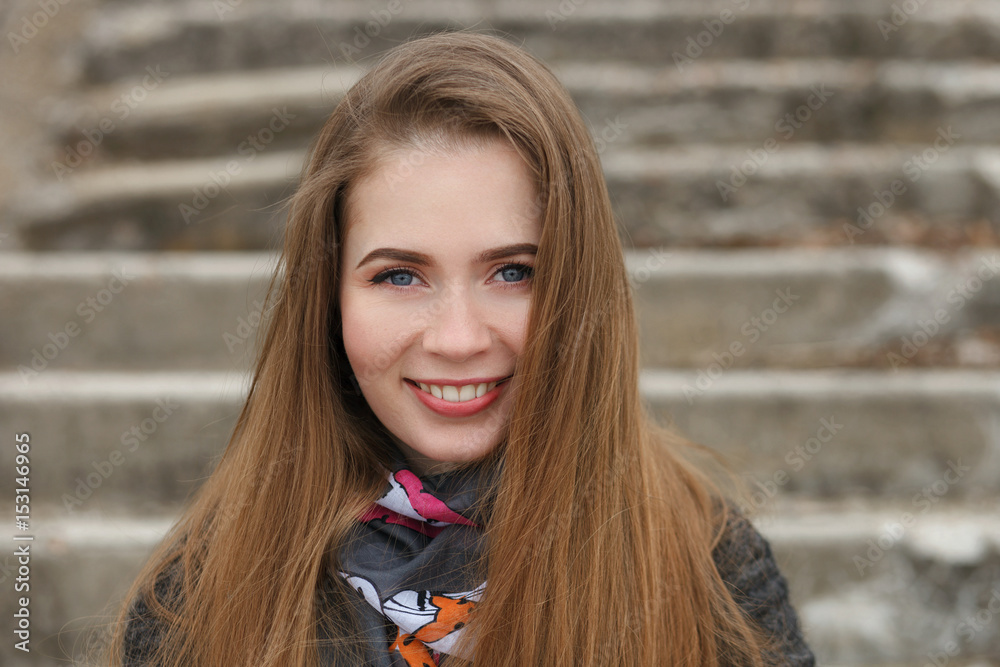 Lifestyle portrait of happy smiling young and pretty adult woman with gorgeous long hair posing in city park with shallow depth of field concrete stairs background Lifestyle portrait of happy smiling young and pretty adult woman with gorgeous long hair posing in city park with shallow depth of field concrete stairs background