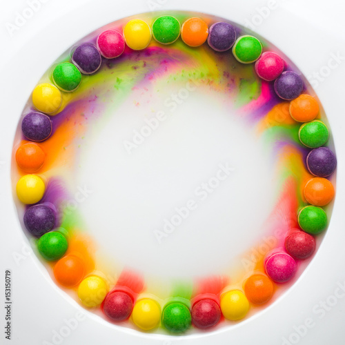 Circle of colored glazed candies on white background. candies melting in several rows, forming a rainbow