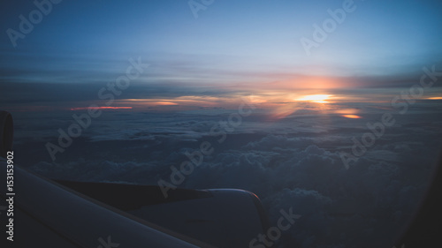 Sunset from 30000 feet wing party visible. Cold tones. Travel concept