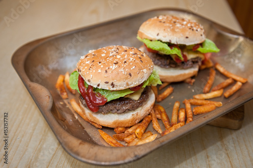 Hamburger with beef, cheese, onion, tomato, sauce and french fries. Homemade burger.