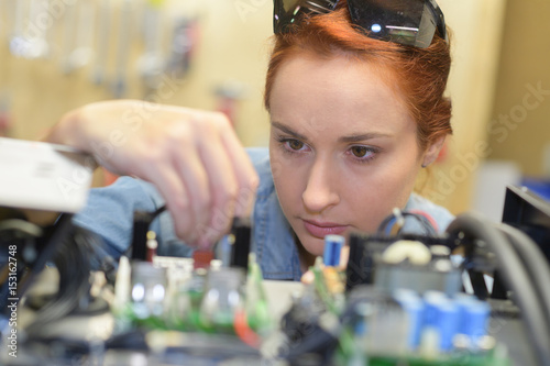 Woman looking closely at electronics board